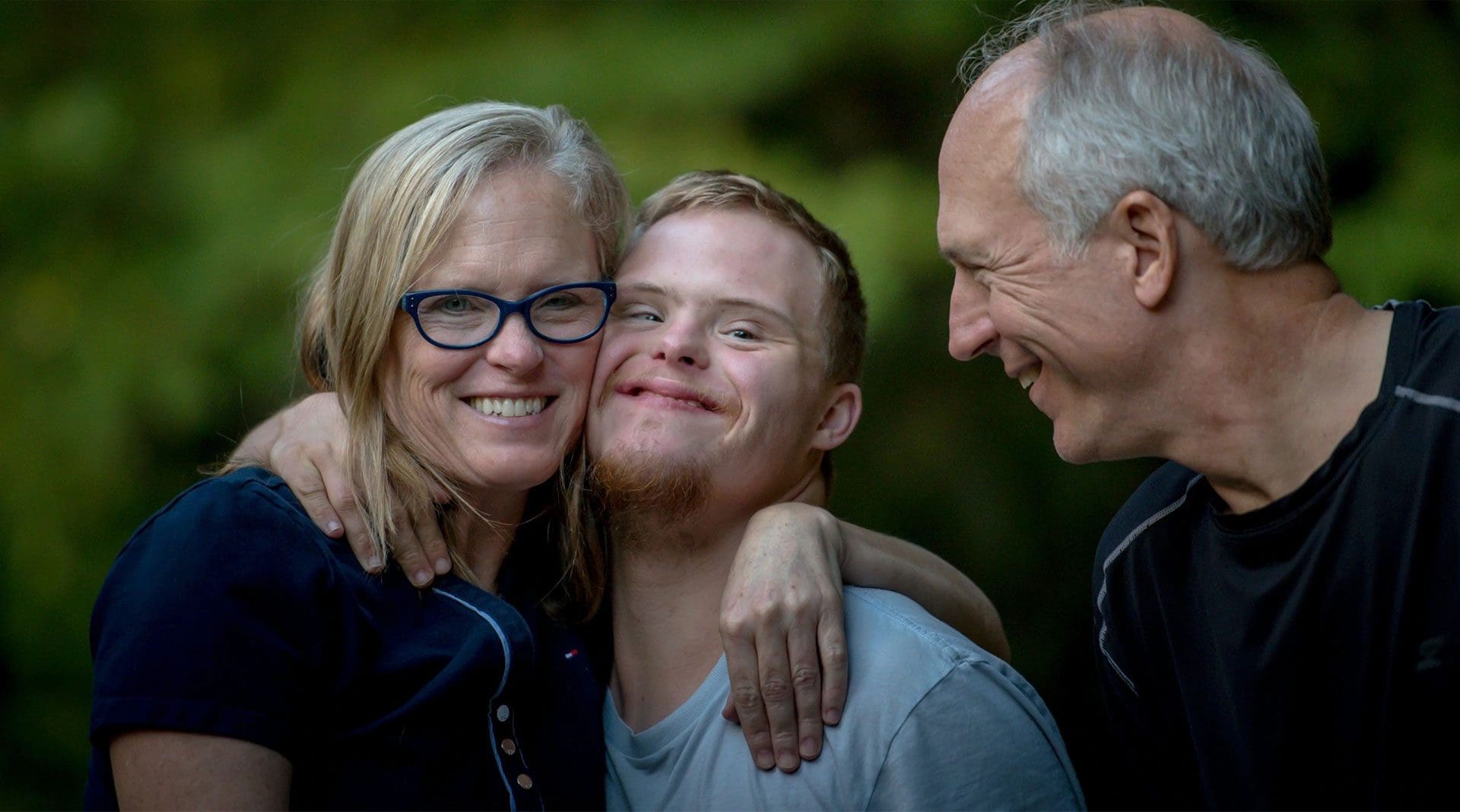 A man and two women are smiling for the camera.